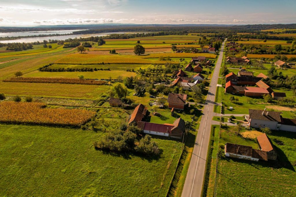 A scenic aerial view of a Croatian countryside village surrounded by golden fields and lush greenery.